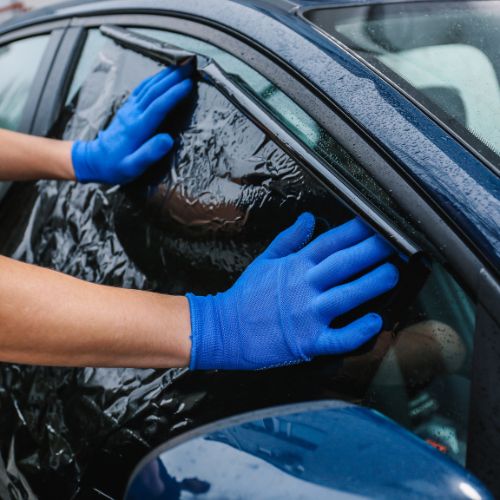 Technician applying full car tint on vehicle in Chicago bay